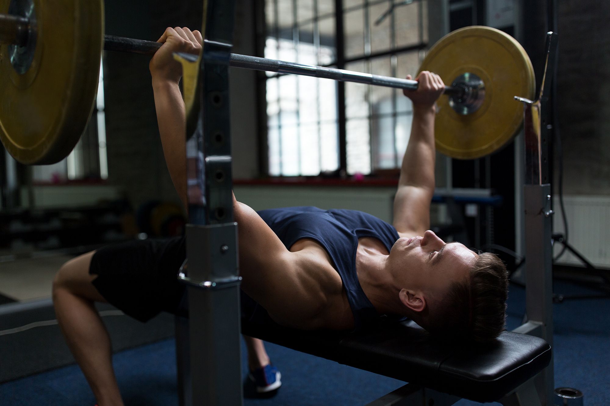 man flexing muscles with barbell in gym