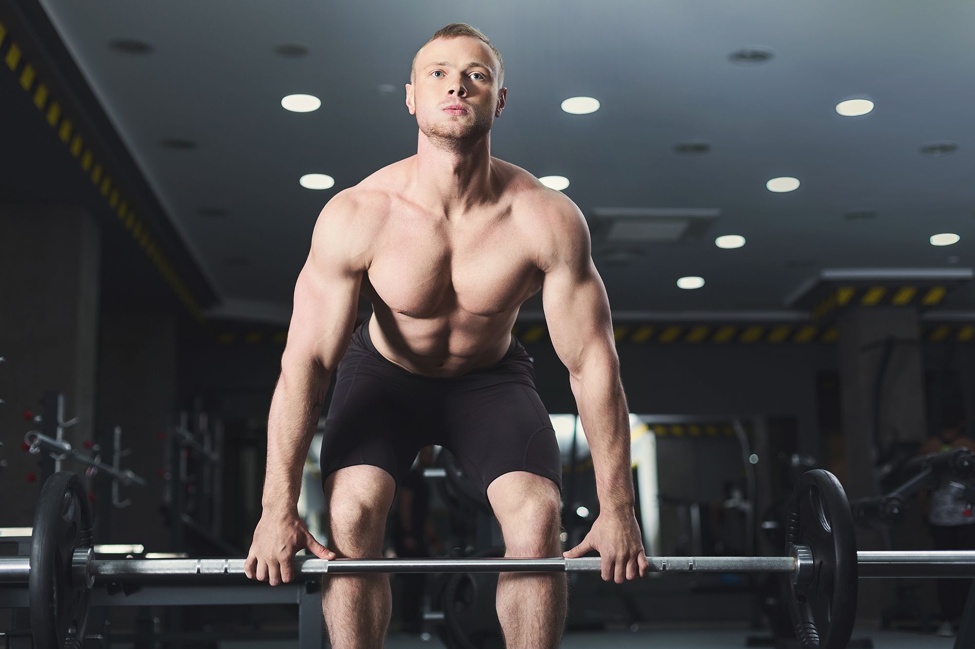 muscular bodybuilder doing heavy deadlifts at gym