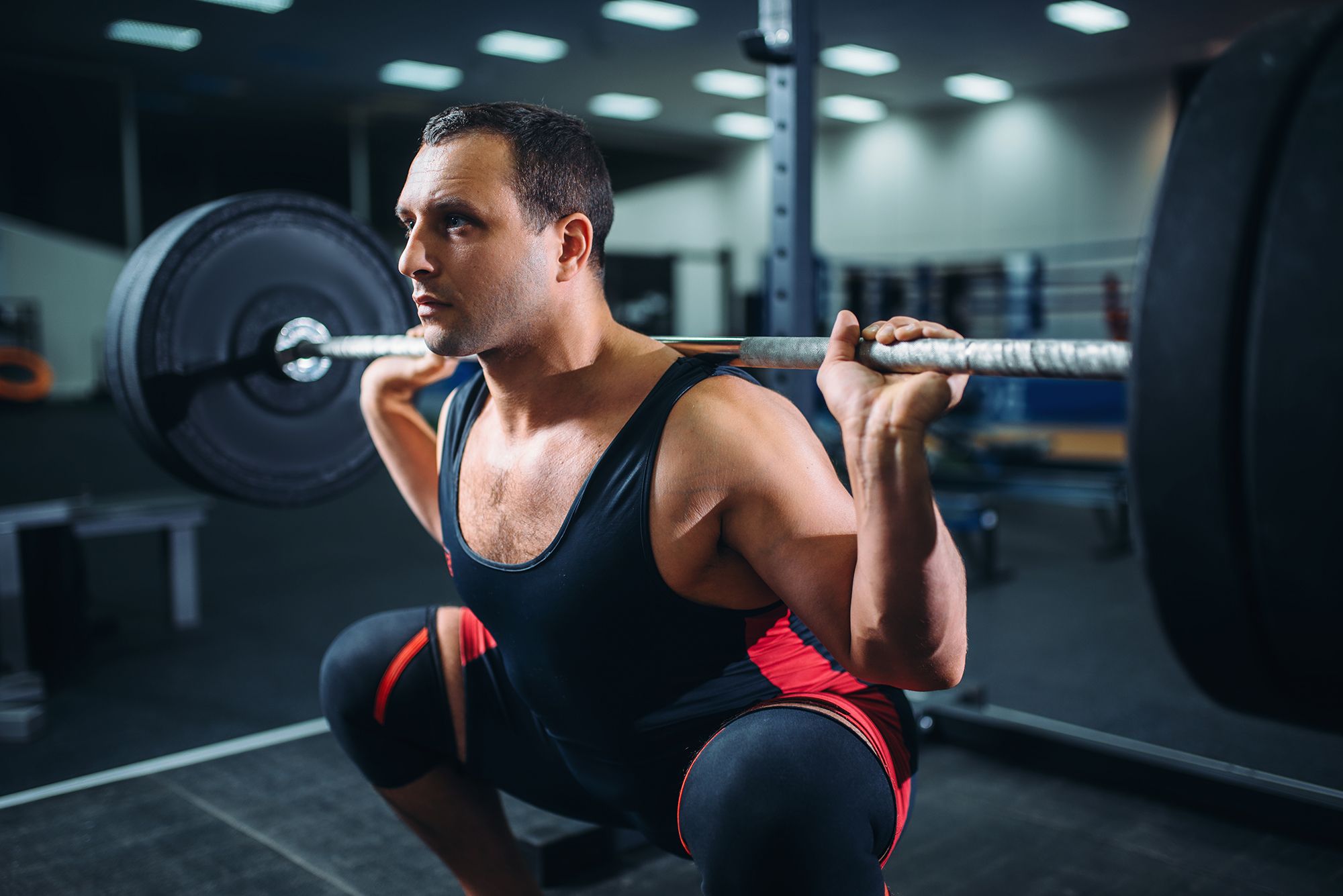 powerlifter doing squats with barbell in gym