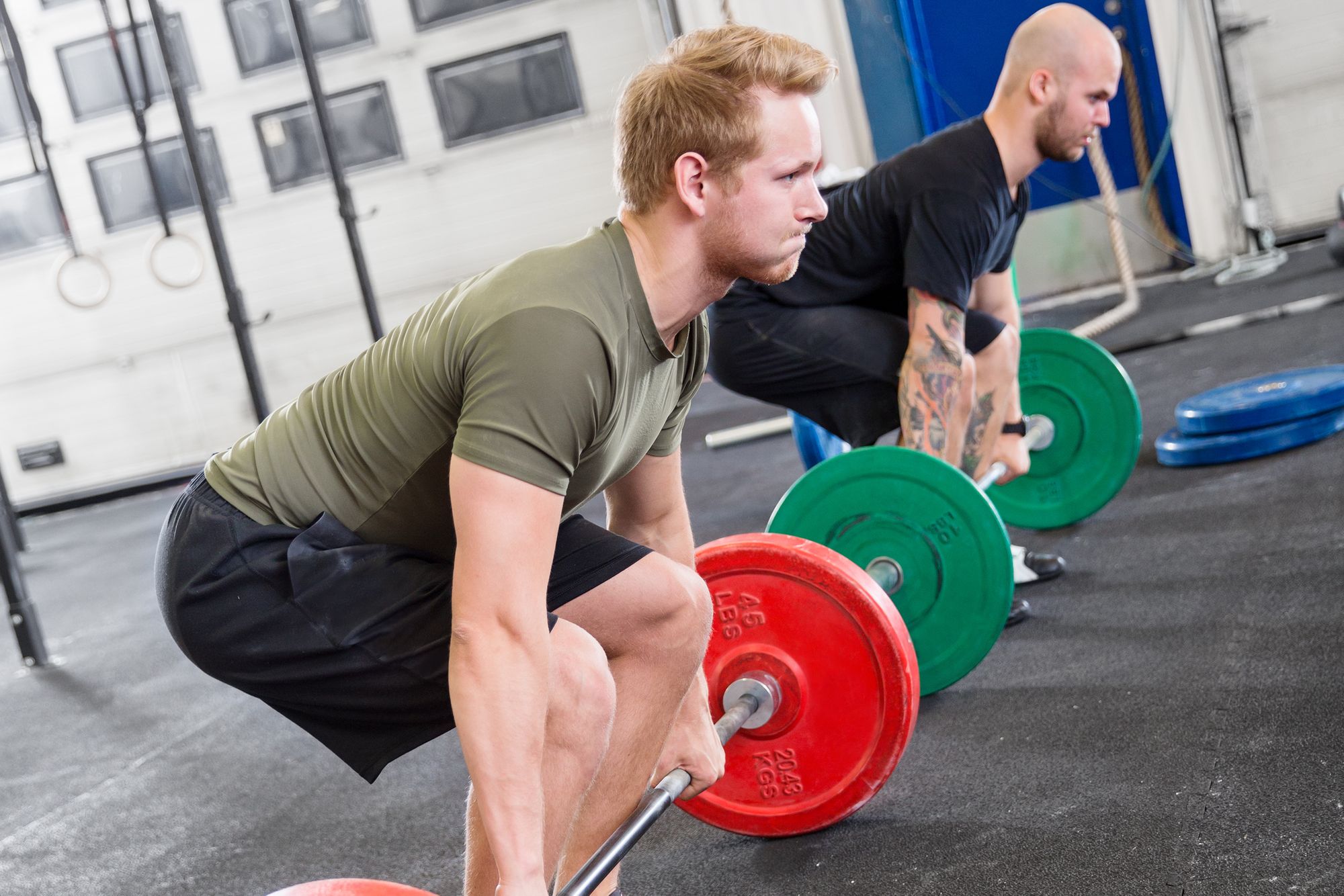 two dedicated men deadlift at fitness gym